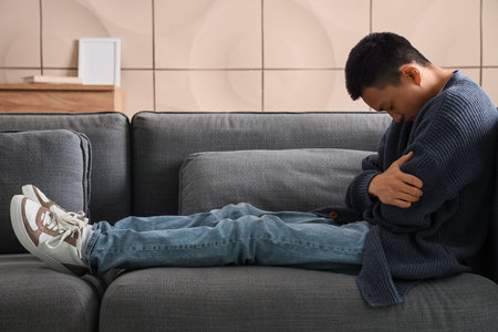 Young Asian man sitting on sofa at homeの写真素材