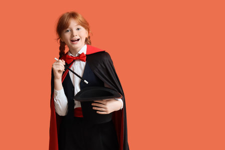 Young magician showing magic trick with hat on orange backgroundの写真素材