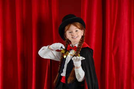 Young magician showing magic trick with stars on red curtain backgroundの写真素材