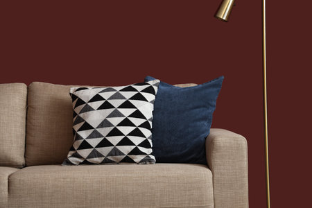 Interior of stylish living room with cozy gray sofa and standard lamp near red wall
