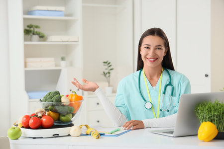 Portrait of female nutritionist with vegetables at table in officeの写真素材