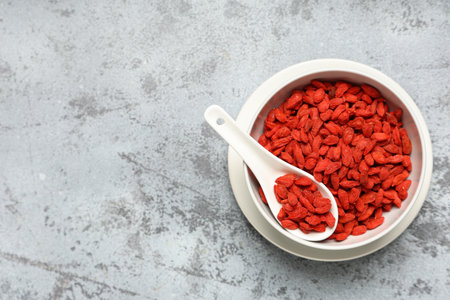 Bowl with dried goji berries on gray grunge background, closeupの写真素材