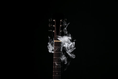 Black guitar with smoke on dark backgroundの写真素材