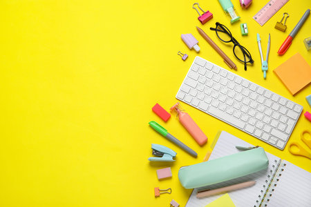 Composition with modern computer keyboard, glasses and different stationery on yellow background