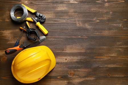 Hardhat and construction tools on wooden background, top view