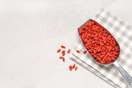 Metal scoop with dried goji berries on white grunge background, closeupの写真素材