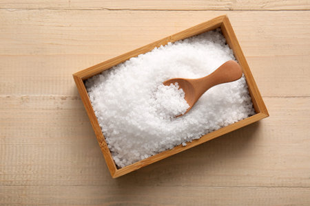 Box with sea salt and spoon on wooden background