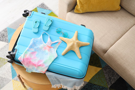 Suitcase with children's swimsuit and beach accessories on table in living room, top viewの写真素材
