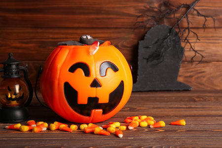 Decorative pumpkin with different sweet candies on wooden background. Halloween celebration