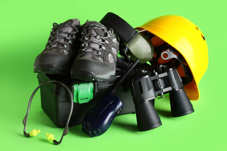 Hardhat with tool box, binoculars and radio transceiver on green backgroundの写真素材