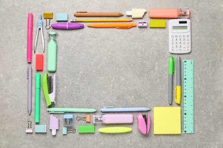 Frame made of different school stationery on gray grunge background