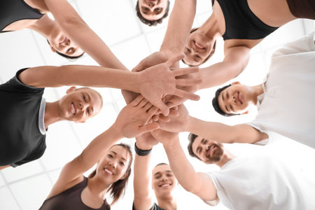 Group of sporty young people putting hands together at gym, bottom viewの写真素材
