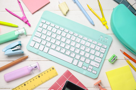Composition with computer keyboard and school supplies on white wooden background, closeup