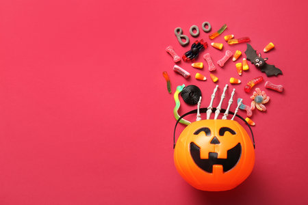 Composition with cauldron in shape of pumpkin, candies for Halloween and word BOO made of plasticine on pink backgroundの写真素材