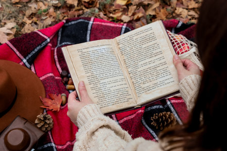 Woman reading book on plaid in autumn park, closeupの写真素材