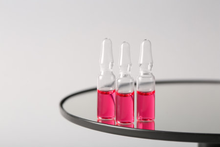 Glass ampoules on table against light backgroundの写真素材