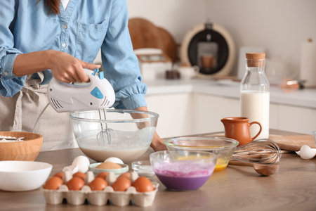 Young woman using mixer at table in kitchenの写真素材