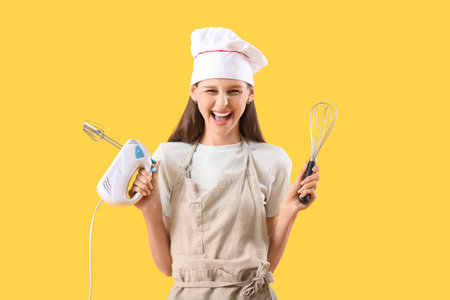 Female chef with mixer on yellow backgroundの写真素材