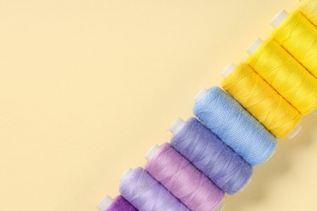 Row of colorful thread spools on beige background