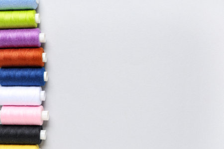 Row of colorful thread spools on gray backgroundの写真素材