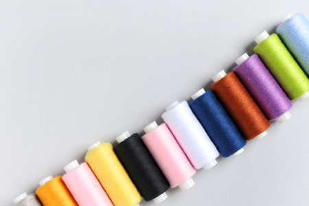 Row of colorful thread spools on gray background