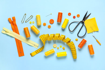 Set of thread spools with measuring tape, scissors, fabric and sewing supplies on blue backgroundの写真素材