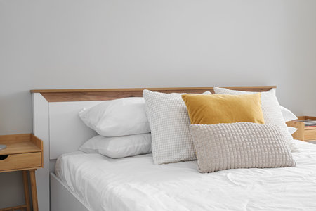 Big bed with soft pillows in light roomの写真素材