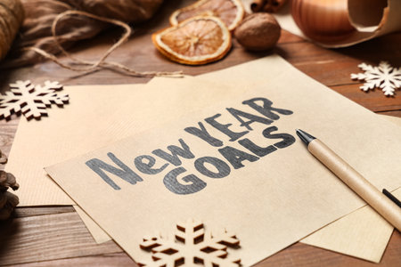 Paper with text NEW YEAR GOALS and snowflakes on wooden background, closeupの写真素材