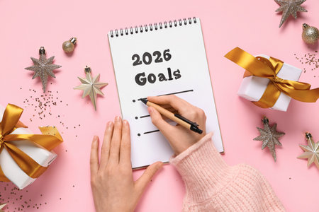 Woman making to do list for 2026 year on pink background