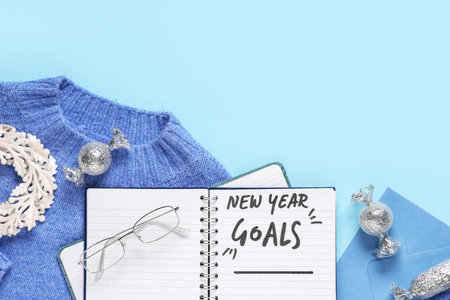 Notebook with empty to do list, sweater and Christmas decor on blue background