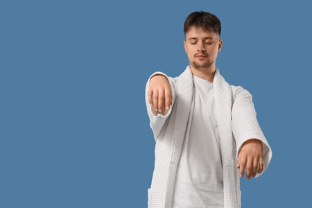 Male sleepwalker in pajamas on blue backgroundの写真素材