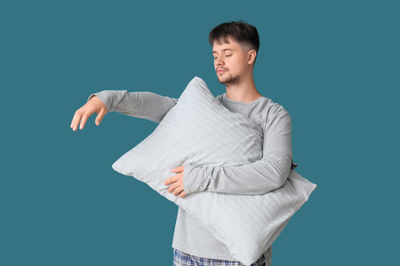 Male sleepwalker with pillow on blue backgroundの写真素材