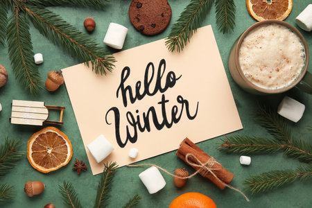 Paper with text HELLO WINTER, treats and Christmas branches on green grunge backgroundの写真素材