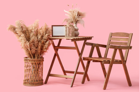 Wooden chair with table and pampas grass on pink backgroundの写真素材