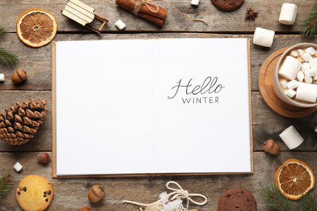 Notebook with text HELLO WINTER and treats on wooden backgroundの写真素材