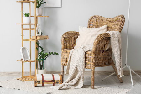 Interior of room with wicker armchair, houseplants, shelving unit and suitcase near white wallの写真素材