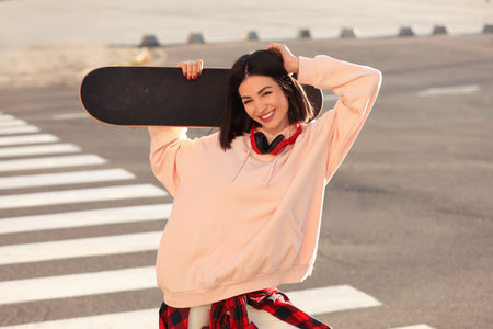 Young woman with skateboard on city street at sunsetの写真素材