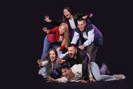 Group of young people reaching for something on dark background.の写真素材