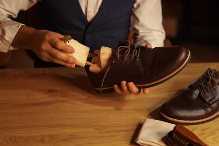 Man putting shoe tree into boot in room at night, closeupの写真素材