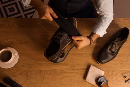Man wiping shoe on table in room at night, top viewの写真素材
