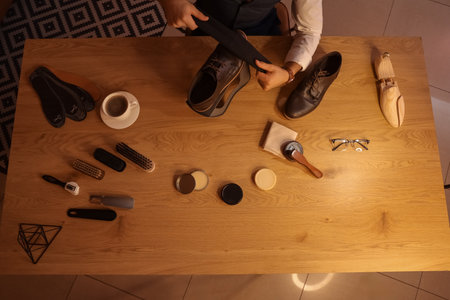 Man wiping shoe on table in room at night, top viewの写真素材