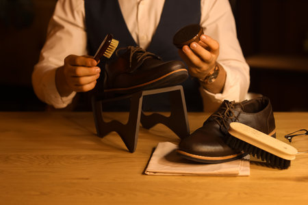 Man polishing shoes with brush in room at nightの写真素材