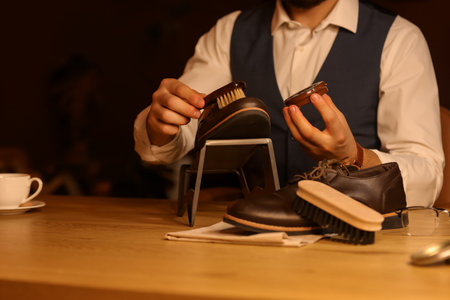 Man polishing shoes with brush in room at nightの写真素材