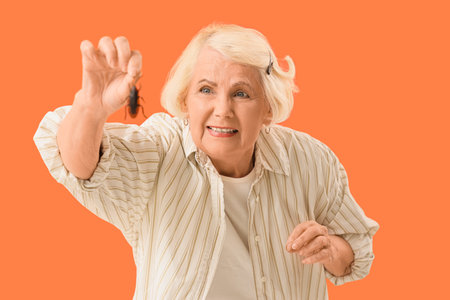 Senior woman with cockroach on orange backgroundの写真素材