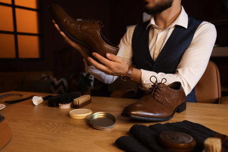 Man with polished shoes at table in dark roomの写真素材
