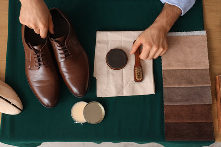 Male shoemaker's hands with leather shoes and polish at table in workshop, top viewの写真素材