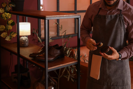 Male shoemaker with shoe polish in workshopの写真素材