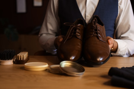 Man with polished shoes at table in dark room, closeupの写真素材