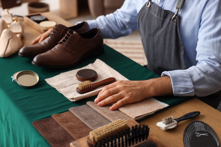 Male shoemaker with leather shoes and polish at table in workshopの写真素材