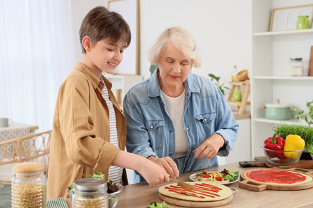 Senior woman with her grandson making pizza in kitchenの写真素材